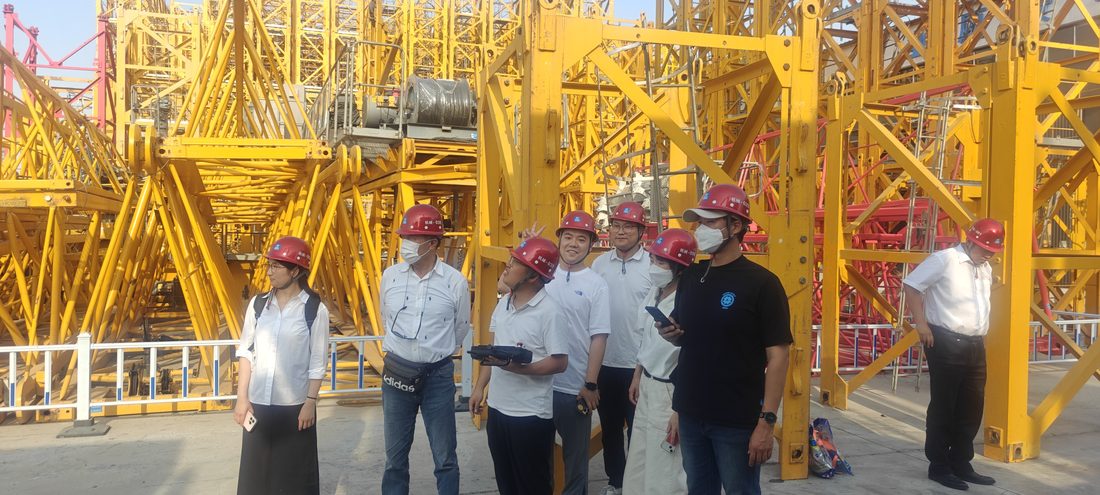 South Korean crane rental delegation inspecting the safety monitoring unit at a rental yard